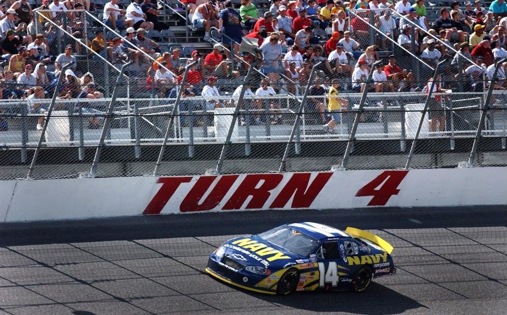 A NASCAR Busch Series stock car race at Darlington Raceway, with cars racing through a turn in front of a full grandstand of spectators.